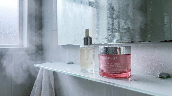 Feel1 PDRN cream jar next to a plain glass dropper bottle of serum on a steamy bathroom shelf